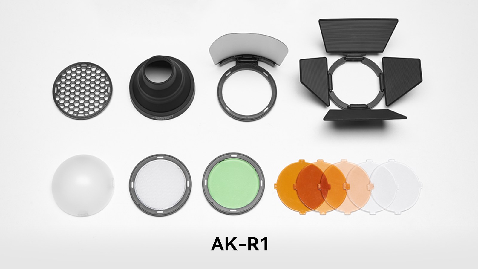 GODOX AK-R1のアクセサリー一式。ハニカムグリッド、スヌート、バウンスカード、バーンドア、ドームディフューザー、色フィルターなどが白い背景に並んでいる。