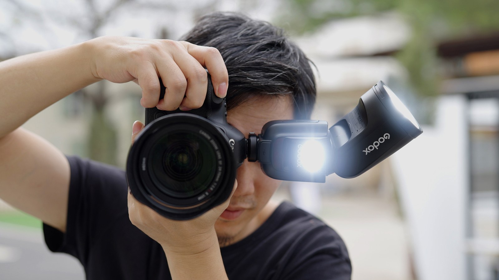カメラを構えた撮影者。ヘッドを上に向けたV1 Proの手前で、小さなサブフラッシュが前方に向かって光っている。