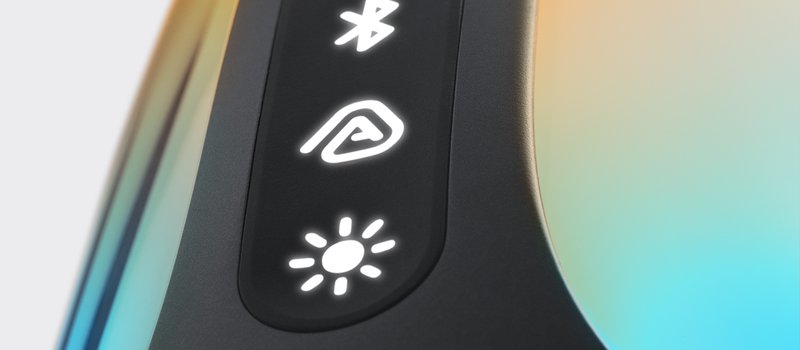 JBL Pulse 6の側面のボタンを大きく写した写真。黒い縦長の帯に、Bluetooth、Auracast、光の3つのボタンが白く光って並び、両側の透明な胴が水色と黄色に光っている。