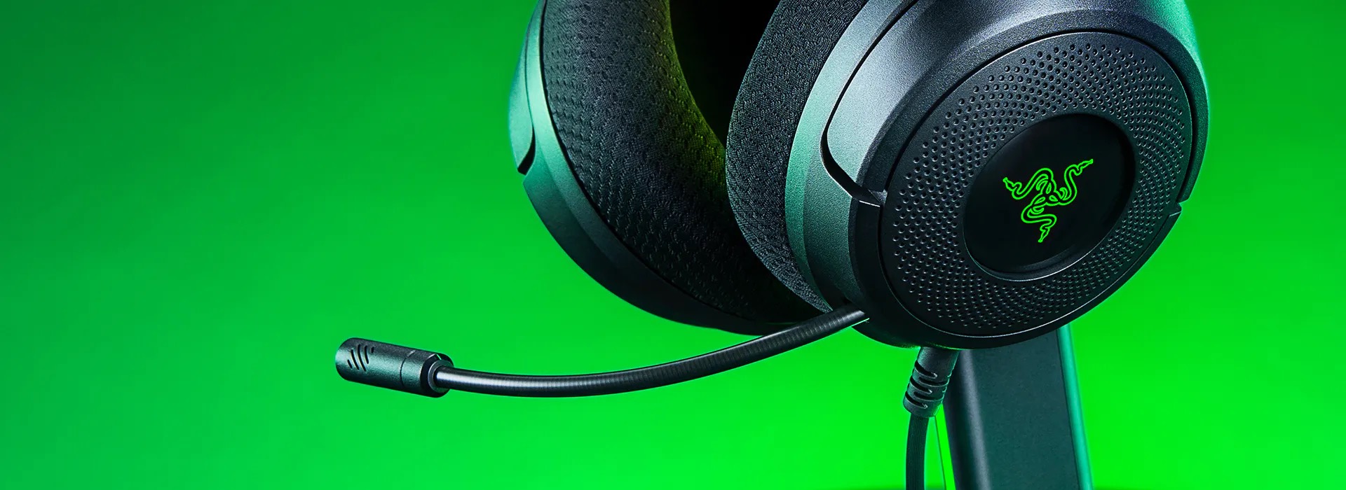 緑色の背景に置かれたRazer Kraken V4 X Sensa HD Hapticsを横から撮った写真。イヤーカップの前から細いブームマイクが伸びている。