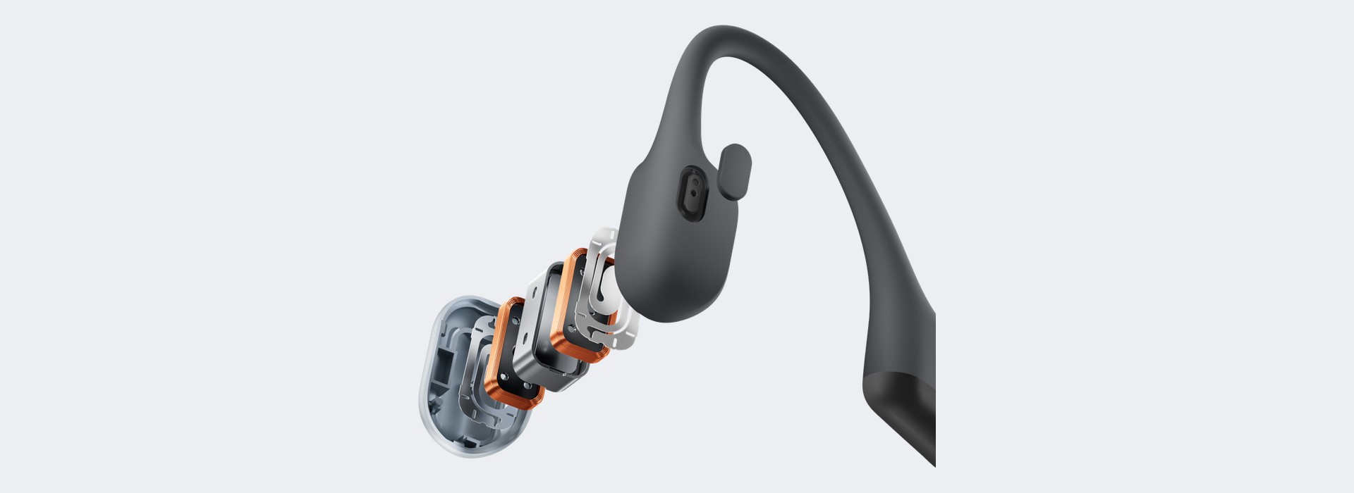 Shokz OpenRun Air 2の骨伝導スピーカーを分解して並べた図。黒い本体から、銀色とオレンジ色の薄い部品が何層も重なって手前に引き出されている。